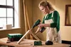 A woman is using a cordless drill to assemble wooden pieces in a workshop setting. Produktbild-Vorschau