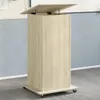 A light wood-tone lectern with a hinged top is shown in a room with a blue wall and gray floor. Náhled obrázku produktu
