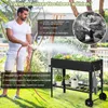A man is watering plants in a raised garden bed in a backyard setting. Voir les images du produit
