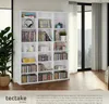 A white shelving unit filled with CDs, DVDs, and decorative items, placed in a room with a large window and curtains. The bottom of the image includes a logo and text. Náhled obrázku produktu