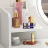A white shelf with various cosmetic products on it, including bottles, lipstick, and an eyeshadow palette. Náhľad obrázku produktu