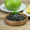 A wooden bowl filled with black shungite crystals, with a green apple and a slice of lemon in the background. Anteprima dell’immagine prodotto