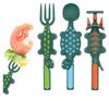 A set of children's utensils shaped like dinosaurs and a shrimp on a fork. Produktbild-Vorschau