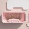 A pink ultrasonic cleaner for glasses is shown with glasses inside, mounted on a pink wall. Náhled obrázku produktu