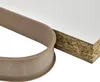 A close-up shot of a beige U-shaped edge banding strip next to a piece of white particle board. Náhľad obrázku produktu