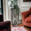 A plant stand with a potted plant is placed next to a chair in a room. Anteprima dell’immagine prodotto