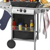 A close-up view of a gas grill with various accessories and condiments. Produktbild-Vorschau