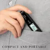A hand holding a black thermometer is placed inside a gray shirt pocket. Produktbild-Vorschau