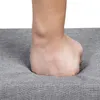 A person's fist is pressing into a gray upholstered surface, demonstrating its softness or cushioning. Náhľad obrázku produktu
