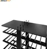 A close-up view of the top section of a black metal wine rack, showing the top surface with several screws and pre-drilled holes, and the beginning of the tiered shelving structure below. Podgląd zdjęcia produktu