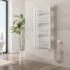 A modern bathroom with a white electric towel warmer mounted on a tiled wall, next to a large potted plant and a window. Voir les images du produit