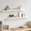Two white floating shelves mounted on a white wall, displaying various decorative items. Produktbild-Vorschau