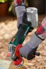 A person wearing gloves is using a cordless angle grinder with a wire brush attachment on a metal object outdoors. Produktbild-Vorschau