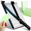 A paper cutter is shown with a hand holding a small piece of paper near it. Produktbild-Vorschau