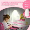 A young child is sitting at a pink desk with a lamp and drawing supplies. Produktbild-Vorschau