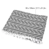 A table runner with a geometric pattern and pom-pom trim is shown from a diagonal angle. Podgląd zdjęcia produktu
