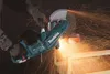A person wearing gloves is using a Makita angle grinder to cut a piece of wood, creating a shower of sparks. Voir les images du produit