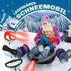 Two children are sitting on a sled in the snow, with a winter landscape in the background. Produktbild-Vorschau