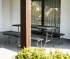 A picnic table and benches are set up on a patio, with a large window and curtains in the background. Podgląd zdjęcia produktu
