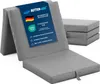 A folded gray mattress is shown in the foreground, with a stack of folded mattresses in the background. Produktbild-Vorschau