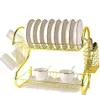 A gold-colored two-tier dish drying rack with plates, cups, and cutlery. Voir les images du produit