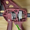 A close-up view of the internal mechanism of a clamp, showing springs and metal components. Náhled obrázku produktu