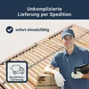 A delivery man is standing next to a bed frame, holding a clipboard and a box. Produktbild-Vorschau