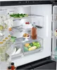 Interior view of an open refrigerator, showcasing various food items and storage compartments. Produktbild-Vorschau