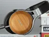 A close-up shot of a pair of Denon headphones resting on a stack of books. Náhled obrázku produktu