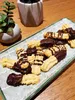 A plate of chocolate-dipped cookies sits on a wooden table next to a potted succulent plant. Voir les images du produit