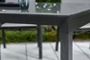 Close-up of a table corner and a glass on a table, with outdoor greenery in the background. Produktbild-Vorschau