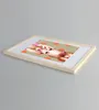 A framed picture with a woman's face and orange polka dots on a beige background, placed on a light gray surface. Produktbild-Vorschau