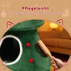 A close-up of a green cat tree designed like a Christmas tree, with a hand brushing it. The background shows a living room setting with a couch and lamp. Anteprima dell’immagine prodotto