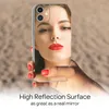 A hand holding a smartphone with a mirrored back that reflects a woman's face. Produktbild-Vorschau