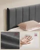 A close-up of a bed frame headboard with inset images showing fabric texture and a hand pressing into a mattress. Náhled obrázku produktu