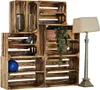 A set of wooden crates stacked to form a shelving unit, with decorative items and a plant placed on and within them. A floor lamp stands to the right. Anteprima dell’immagine prodotto