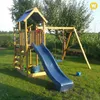 A wooden playground set with a blue slide and swing set, set up on a grassy lawn with trees and foliage in the background. Anteprima dell’immagine prodotto
