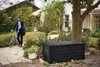 A man in a suit is standing next to his bicycle in a garden, with a large black storage box in the foreground. Produktbild-Vorschau