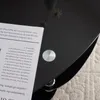 A close-up of a black glass table with a book on it. Podgląd zdjęcia produktu
