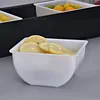 A close-up view of a white container filled with sliced lemons, placed in front of a black bar or tray. Produktbild-Vorschau
