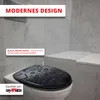 A black toilet seat with water droplets on it, placed on a white toilet bowl, with marble-tiled walls in the background. Produktbild-Vorschau