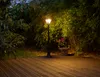 A solar garden lantern illuminates a wooden deck at dusk, with lush greenery in the background. Produktbild-Vorschau