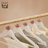 Several white wooden hangers with cedar wood accents are hanging from a wooden rod, displaying various clothing items. Anteprima dell’immagine prodotto