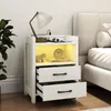 A white nightstand with two drawers and an open shelf with LED lighting, placed next to a bed. Produktbild-Vorschau