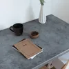 A desk with a mug, a small bowl, and notebooks on a gray surface. Produktbild-Vorschau