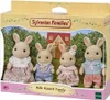 A Sylvanian Families Milk Rabbit Family toy set in its packaging, displayed with a house and garden scene in the background. Podgląd zdjęcia produktu