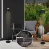 A split image showing a black LED floor lamp indoors on the left and outdoors on the right, with a circular inset showing the lamp in three different sizes. Produktbild-Vorschau