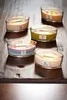 Five scented candles in glass containers are arranged on a wooden surface. Voir les images du produit