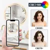 A bathroom scene with a mirror and a hand holding a phone showing the mirror's reflection, alongside comparison images of a person's face under different CRI ratings. Anteprima dell’immagine prodotto