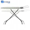 An ironing board with a zigzag pattern cover and an extendable wire rack is shown against a white background. The image also shows a ghosted outline of the ironing board in a lower position, suggesting adjustability. Produktbild-Vorschau